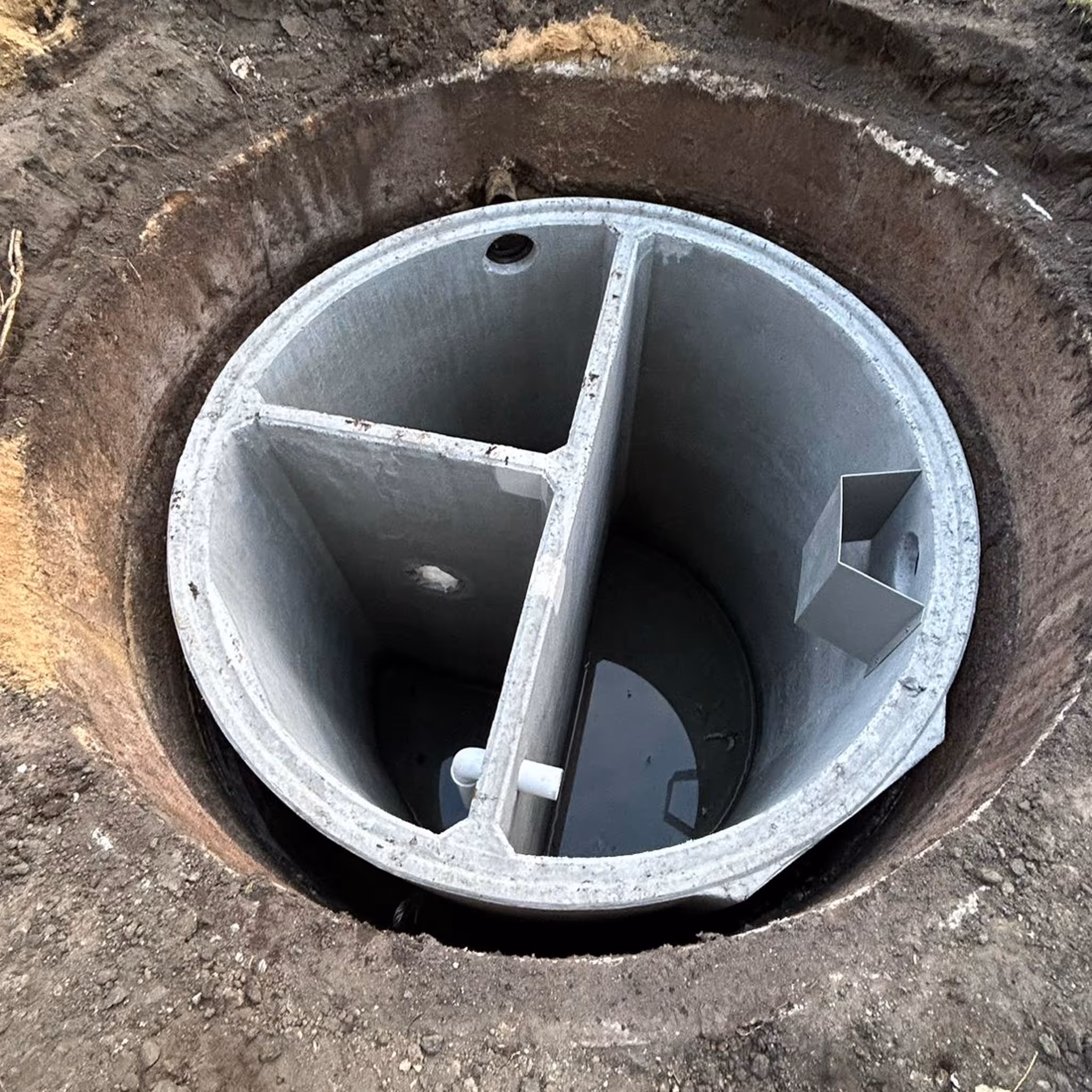 Dreikammergrube aus Beton von oben, eingebaut im Erdreich
