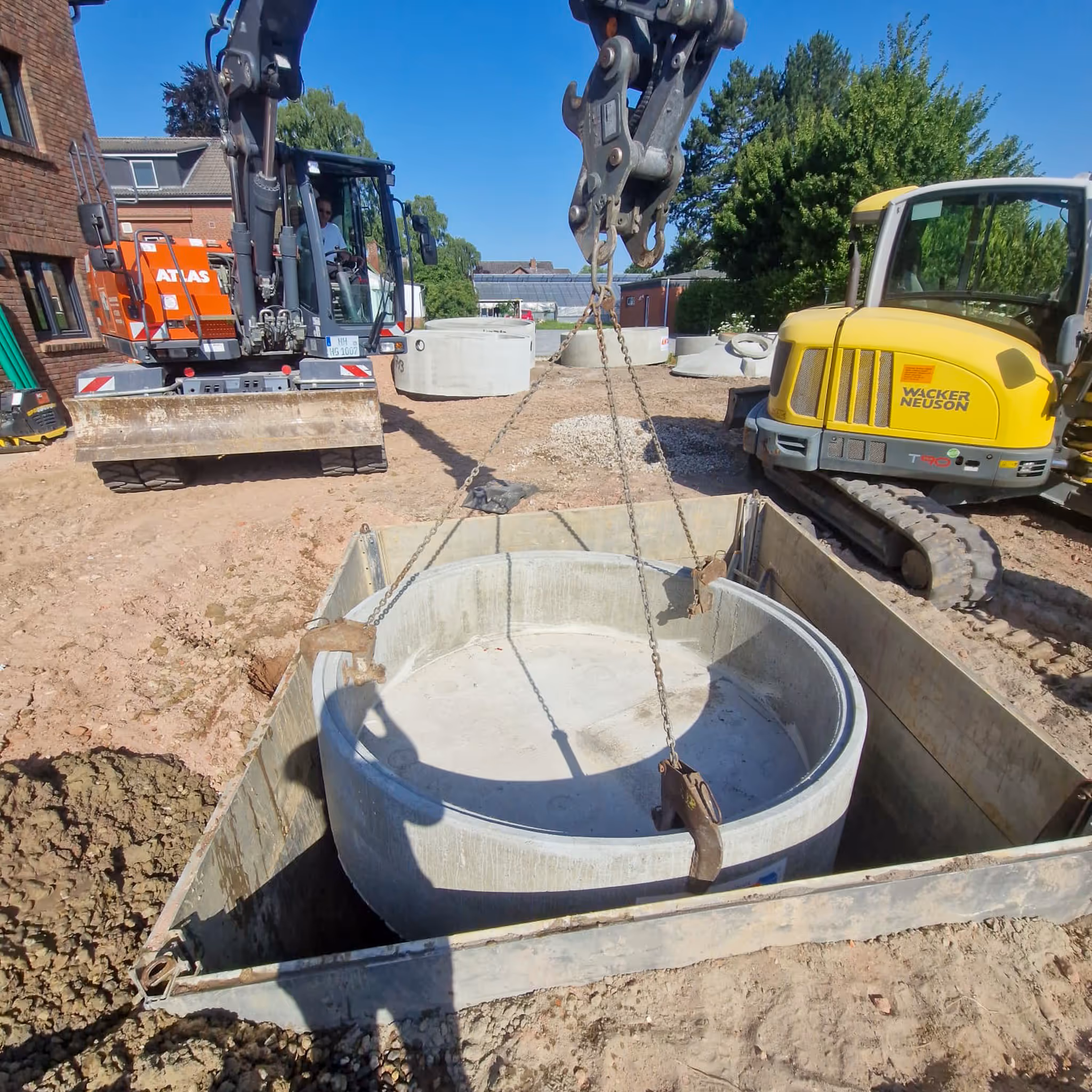 Einsetzen eines Betonbehälters mit Kran, Bagger auf der Baustelle