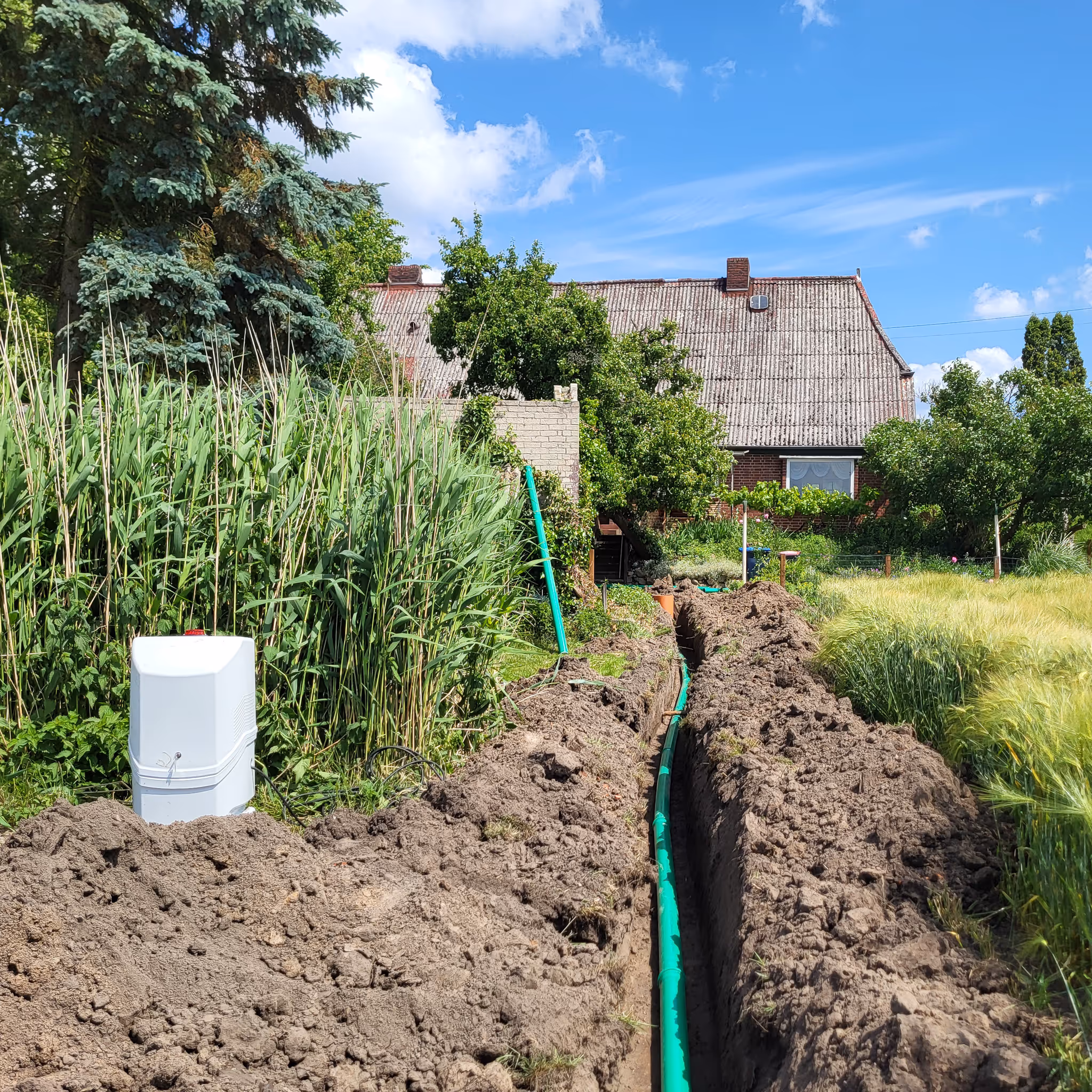 Verlegte Abwasserleitung im Graben und Steuerschrank im Garten