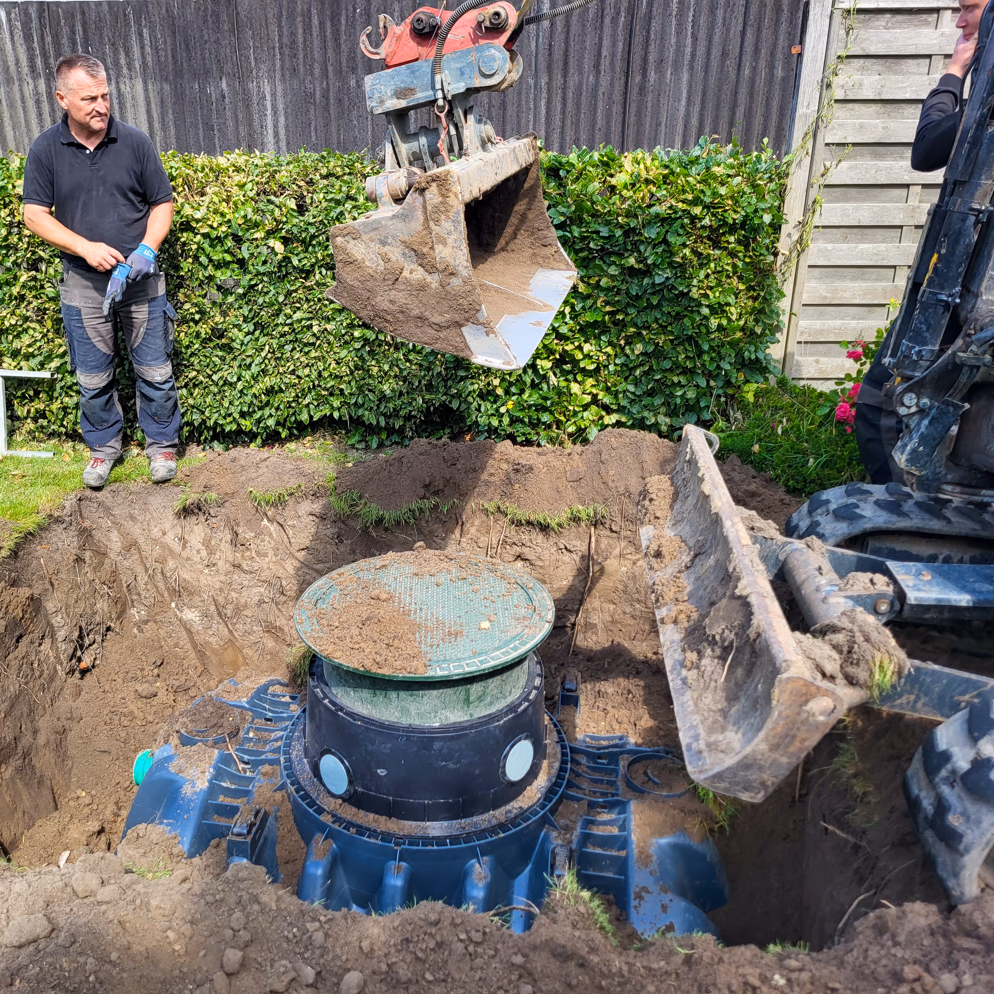 Kunststoff-Kleinkläranlage beim Einbau im Garten mit Bagger